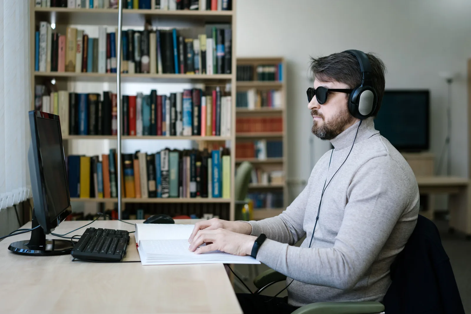 Blind man wearing headphones, working on braille book and computer in a library setting. Accessible workstation case: what the two-week trial actually settled