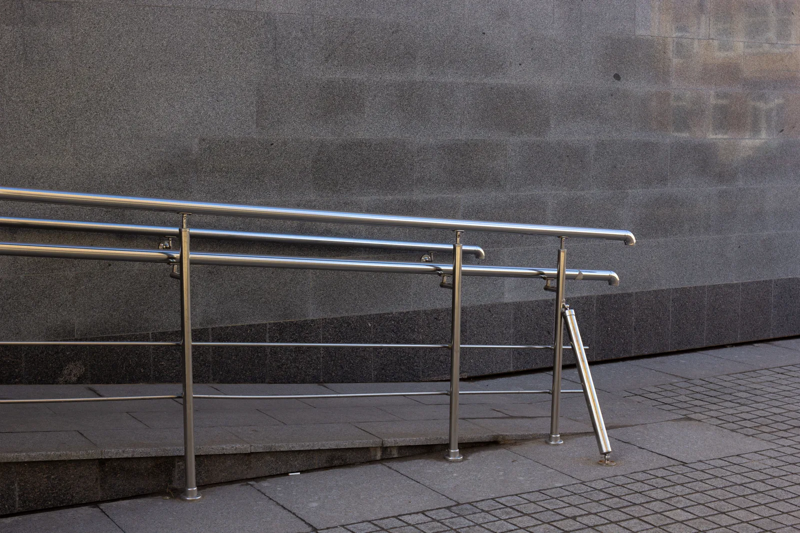 Close-up of a metal handrail and concrete ramp for accessibility in an urban setting. Assistive technology funding through US vocational rehabilitation agencies
