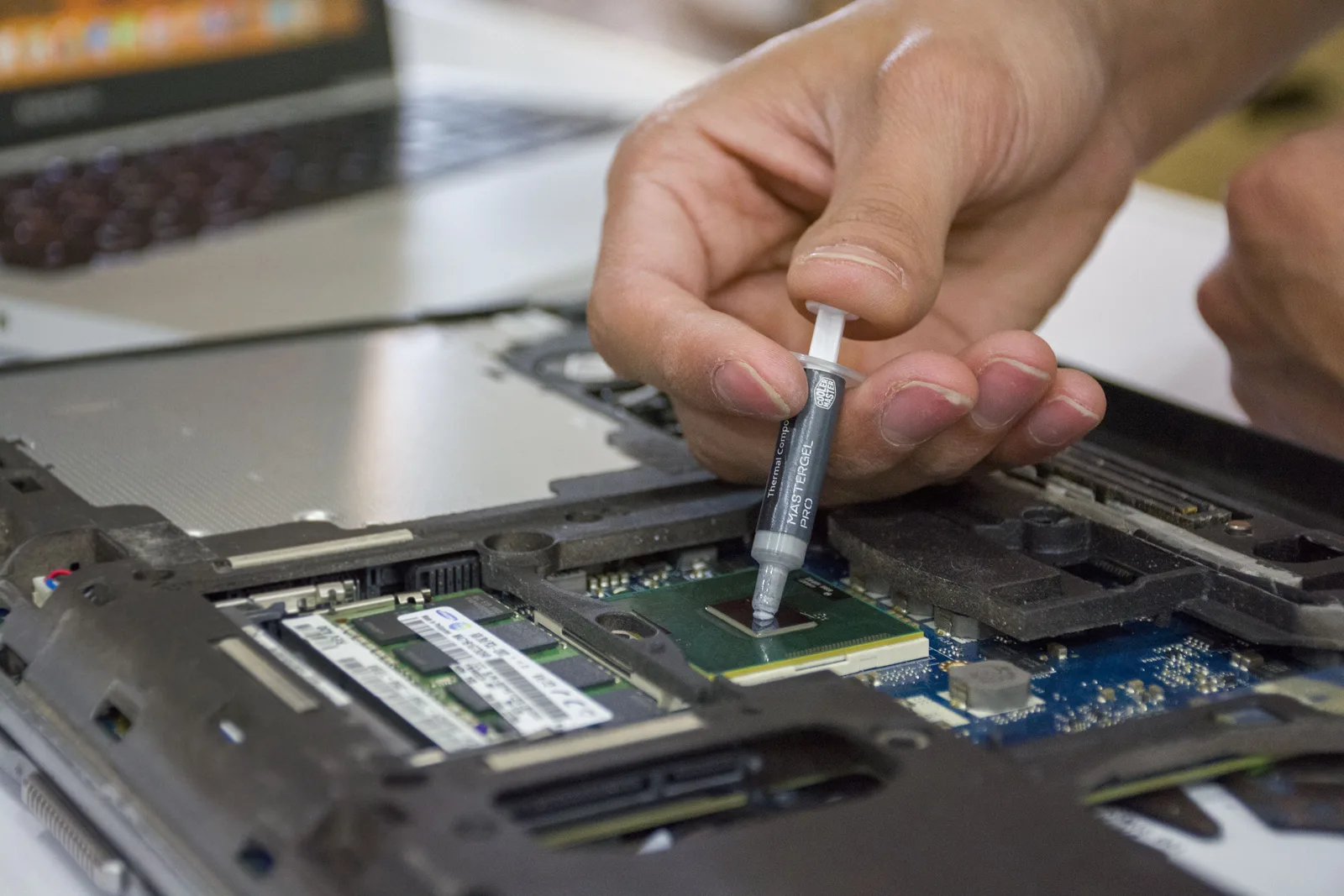 Close-up of hand applying thermal paste to a laptop microchip for maintenance. Common laptop problems: fix slowdowns and crashes