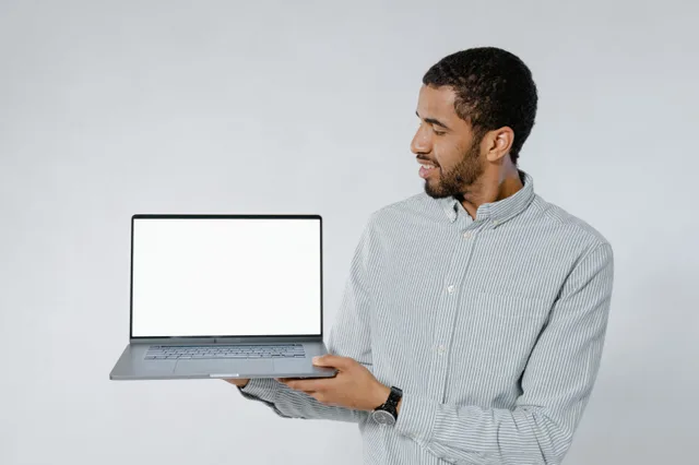 Man in striped shirt showcasing a laptop with blank screen against white background. Laptop replacement case: transfer, setup, retirement