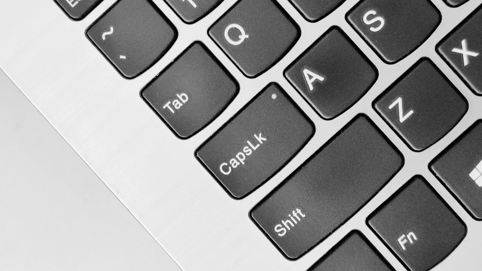 A detailed close-up of a laptop keyboard highlighting the Caps Lock and Shift keys. How to set up accessibility features safely