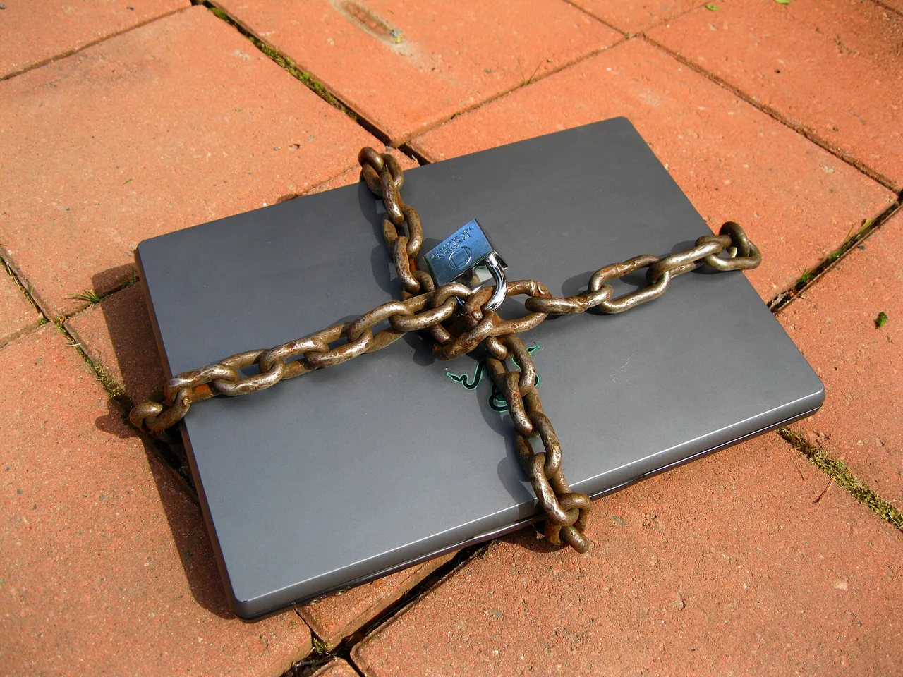 A closed laptop wrapped in chain and secured with a padlock
