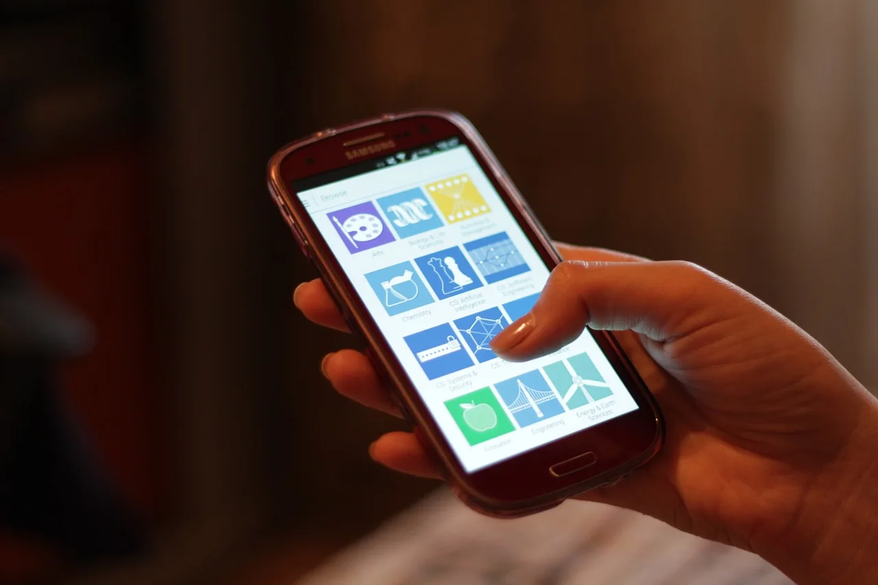 A hand holding a smartphone with its home screen visible